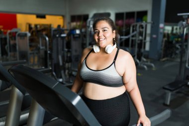 Spor salonundaki kardiyo çalışmasından sonra kendini neşeli hisseden mutlu Latin bir kadının portresi. 