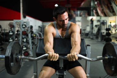 Güçlü spor koçu halter kaldırıyor. Kararlı kaslı adam spor salonunda ağırlık kaldırıyor.