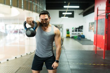 Güçlü bir adam spor salonundaki güçlü antrenmanı için kettlebell ağırlığı kullanıyor. 