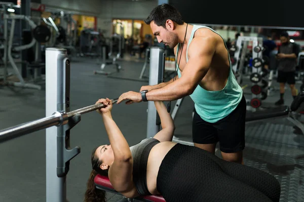 强壮的健身教练在体操馆帮助一位身材魁梧的女士 — 图库照片