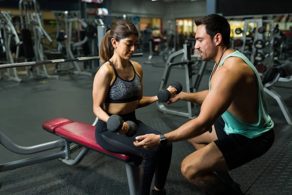 Güzel, güçlü bir kadın halter egzersizleri yapıyor. Halter ağırlık kaldırıyor, erkek spor hocasıyla.