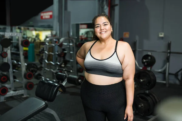 Cheerful beautiful obese woman in sportswear smiling and ready to start a workout at the gym to lose some weight