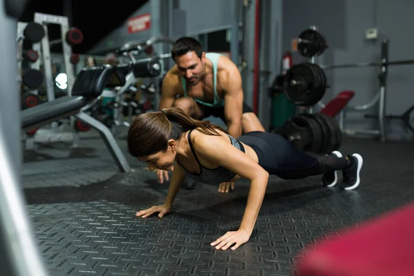 Mujer Joven Deportiva Haciendo Flexiones Con Ayuda Entrenador Entrenamiento Gimnasio — Foto de Stock