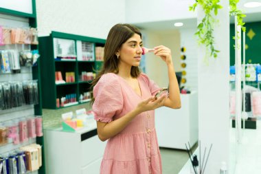 Güzel İspanyol kadın makyaj ürünlerini kozmetik mağazasında test ediyor.