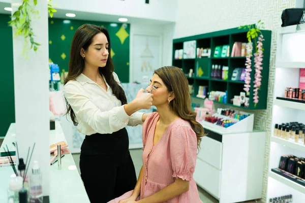 年轻的化妆师用睫毛膏护发素在化妆品店做美容示范 — 图库照片
