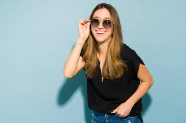 Güzel esmer kadın, güneş gözlükleriyle şık görünürken stüdyoda iyi vakit geçiriyor.