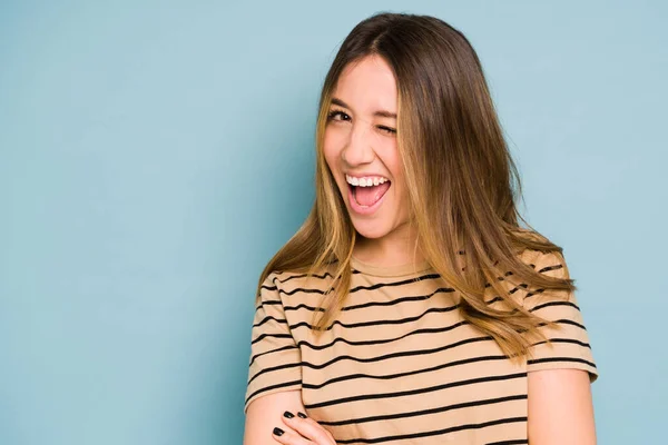 Good looking woman with brown hair having fun and winking while looking flirty in a studio