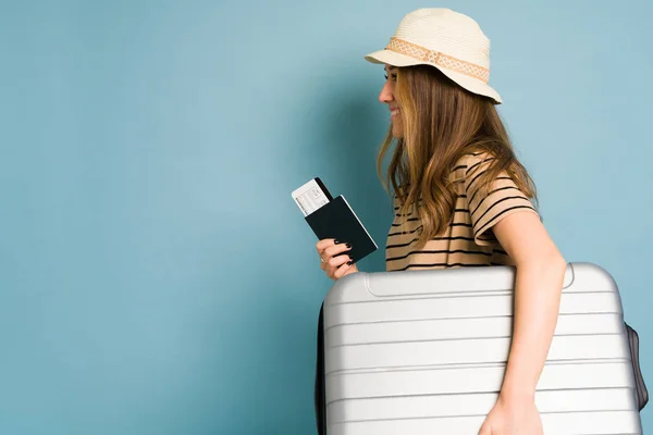 帽子をかぶった女性のプロフィールビューとスタジオでの旅行の準備ができているスーツケースを運ぶ — ストック写真