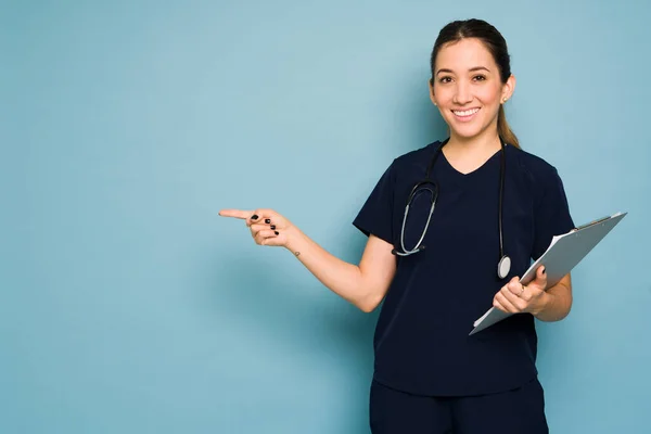 Jovem Médico Caucasiano Sorrindo Apontando Para Espaço Cópia Fundo Azul — Fotografia de Stock