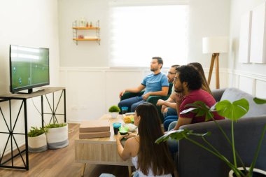 İspanyol bir sporcunun TV 'de maç izleyip pizza yerken yan görüntüsü. 
