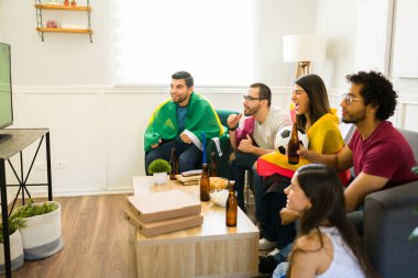 Mutlu spor fanatikleri kanepede takılıp bira içerken TV 'de maç izliyorlar.