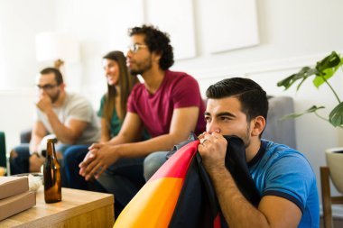 Stresli futbol taraftarı elinde bir Almanya bayrağı tutuyor ve televizyonda futbol maçı izlerken stresli hissediyor