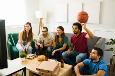 Oturma odasında basketbol oynarken gülümseyen genç kadın ve erkekler.