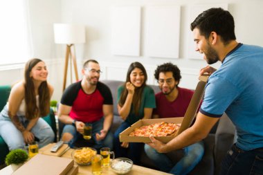 Elinde pizza kutusuyla arkadaşlara yemek getiren mutlu genç bir adam. 