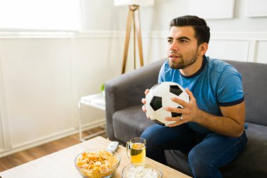 Yakışıklı genç adam, televizyondaki bir futbol maçında skordan endişe ediyor. 