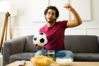 Salondaki çekici genç adam şampiyonluğu kazandıktan sonra en sevdiği futbol takımı için tezahürat yapıyor.