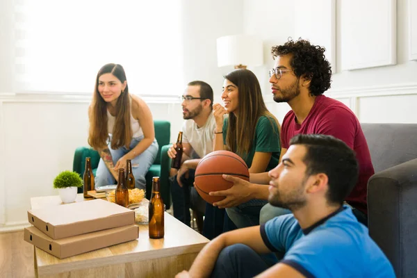 有魅力的一群朋友一边吃披萨 一边喝啤酒 一边在电视上看篮球赛 — 图库照片