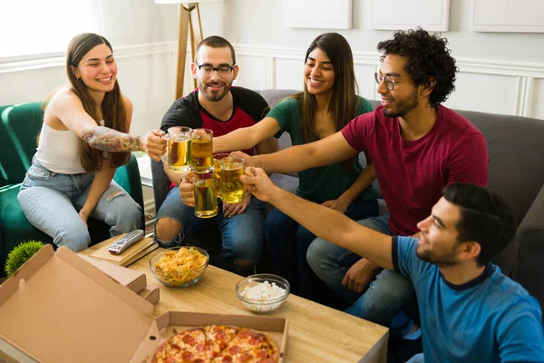 快乐多姿多彩的朋友们一边在客厅里与比萨饼聚会 一边举杯庆祝 — 图库照片