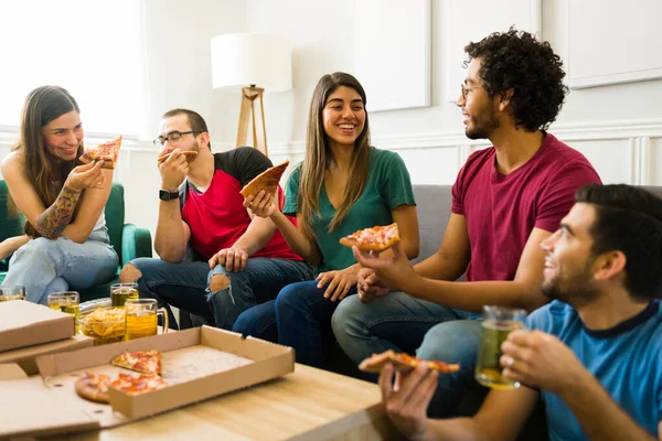 20代の幸せな友人たちは リビングルームでピザを食べながら一緒に笑って楽しんでいます — ストック写真