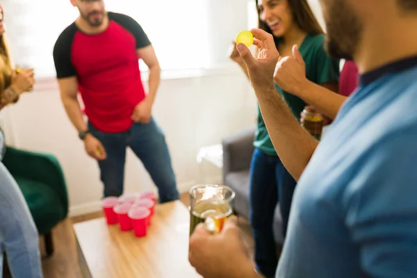 看到一个年轻人一边喝啤酒 一边和许多朋友一起玩啤酒乒乓球的情景 — 图库照片