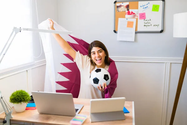 在观看世界杯和在家里办公时 使用国旗的漂亮女人感到兴奋和微笑 — 图库照片