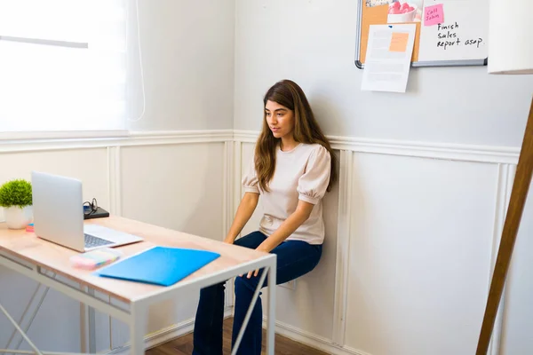 Freelancer woman staying active and healthy by working out while working from home at her desk