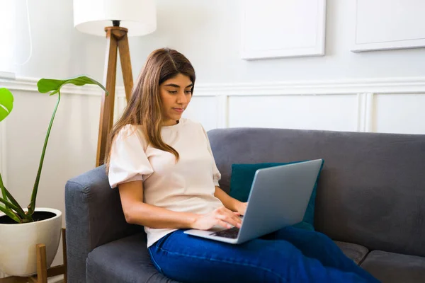 在沙发上的漂亮女人在笔记本电脑上打字 在做家庭办公室和自由职业时放松身心 — 图库照片