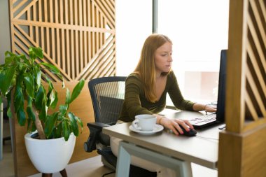 Ofis masasında işini bitirirken bilgisayarda yazan ve çalışan çekici beyaz kadın.