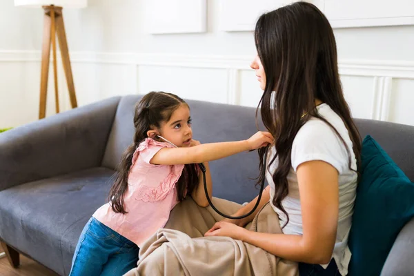 Cute Latin Kid Playing Doctor Game While Using Stethoscope Her — Zdjęcie stockowe