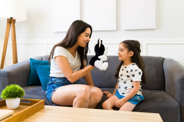 어머니가 인형을 이용하여 재미있는 놀이를 소파에 딸에게 이야기를 들려주는 — 스톡 사진