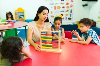 Anaokulu öğretmeni abaküs kullanarak sayıları öğretiyor ve anaokulu çocuklarına kadar sayıyor.