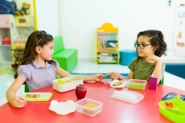 Küçük şirin çocuklar ana okulunda yemeklerini paylaşmayı ve öğle arasında yemek yemeyi öğreniyorlar. 