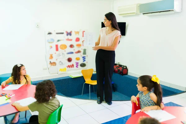 Schöne Vorschullehrerin Gespräch Mit Ihrer Gruppe Von Kindergartenkindern Über Schularbeiten — Stockfoto