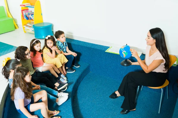Attractive Latin Preschool Teacher Teaching Geography Class Using Globe Lesson — Stockfoto