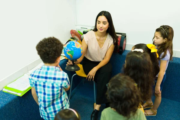 Female Preschool Teacher Smiling Showing Globe Her Group Geography Lesson — Zdjęcie stockowe