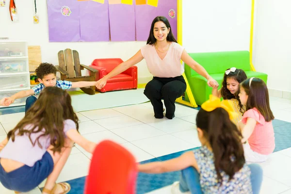 Cheerful Playful Teacher Holding Hands Forming Circle Her Kindergarten Students — ストック写真