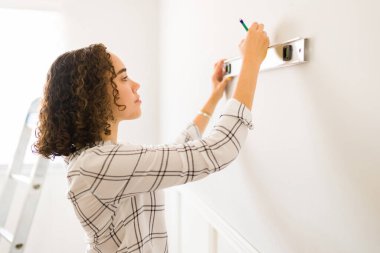 Ev onarımı yapan ve duvarlara dekorasyon malzemesi takan güzel bir kadının profili. 