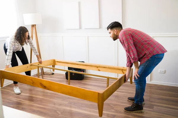 Handy young woman and man assembling a bed frame and furniture together in the bedroom