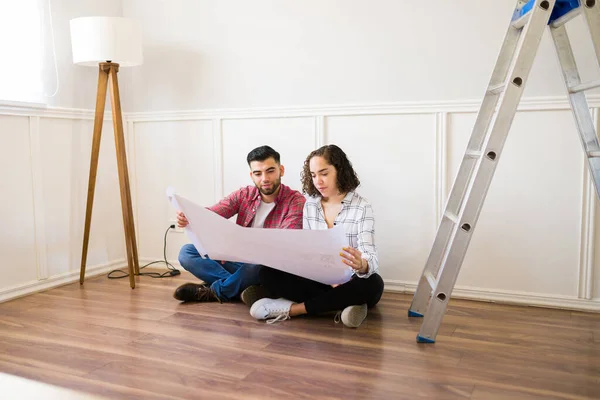 Beautiful Couple Doing Home Renovations Looking Construction Plans While Sitting — Stockfoto
