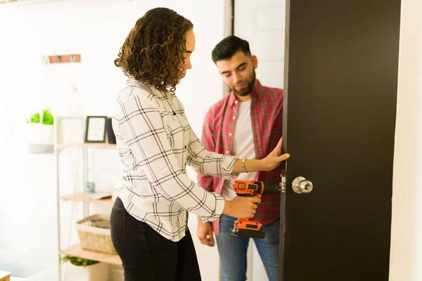 Handy Young Woman Using Drill While Putting New Doorknob Doing — стоковое фото