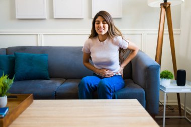 Hasta genç bir kadın karnına dokunuyor ve pankreas iltihabı ya da mide ağrısı yüzünden acı çekiyor.