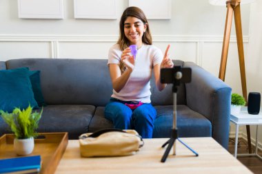Cheerful woman influencer making an online video with a smartphone about feminine sanitary products like the ecological menstrual cup