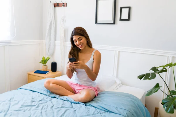 Cheerful Young Woman Pajamas Sitting Bed Laughing While Texting Using — Stock Fotó