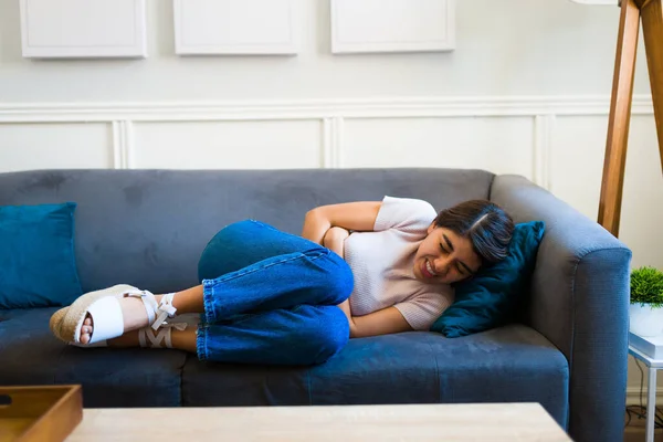 Distressed Young Woman Lying Sofa Looking Pain While Touching Her — Stockfoto