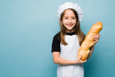 Studio shot of a cute girl smiling wearing a chef's hat baking delicious bread and playing to cook