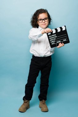 Full length of an adorable little boy using a clapperboard and dreaming to work as a movie director or in entertainment