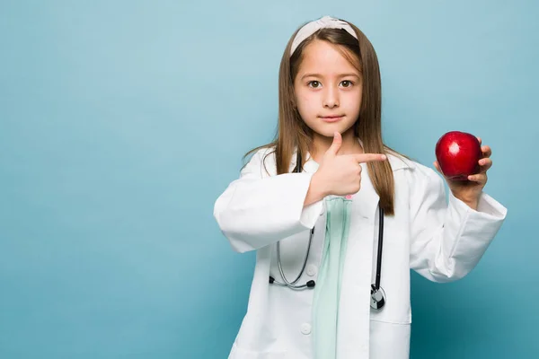 Caucasian Young Kid Doctor Aspiring Career Nutritionist Pointing Apple Blue —  Fotos de Stock