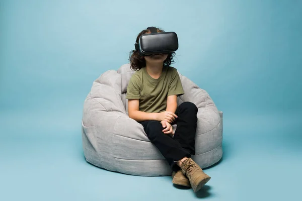 Caucasian Elementary Boy Sitting Kids Chair Wearing Virtual Reality Glasses — Φωτογραφία Αρχείου