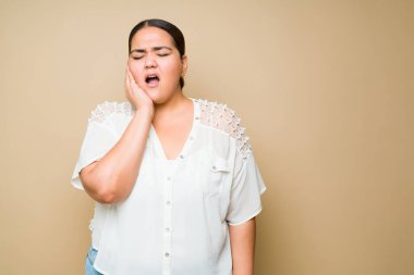 Pained young woman touching her face and suffering from toothache because of cavities or wisdom teeth