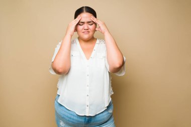 Sad sick obese woman suffering from a bad headache or migraine while feeling stressed and tired
